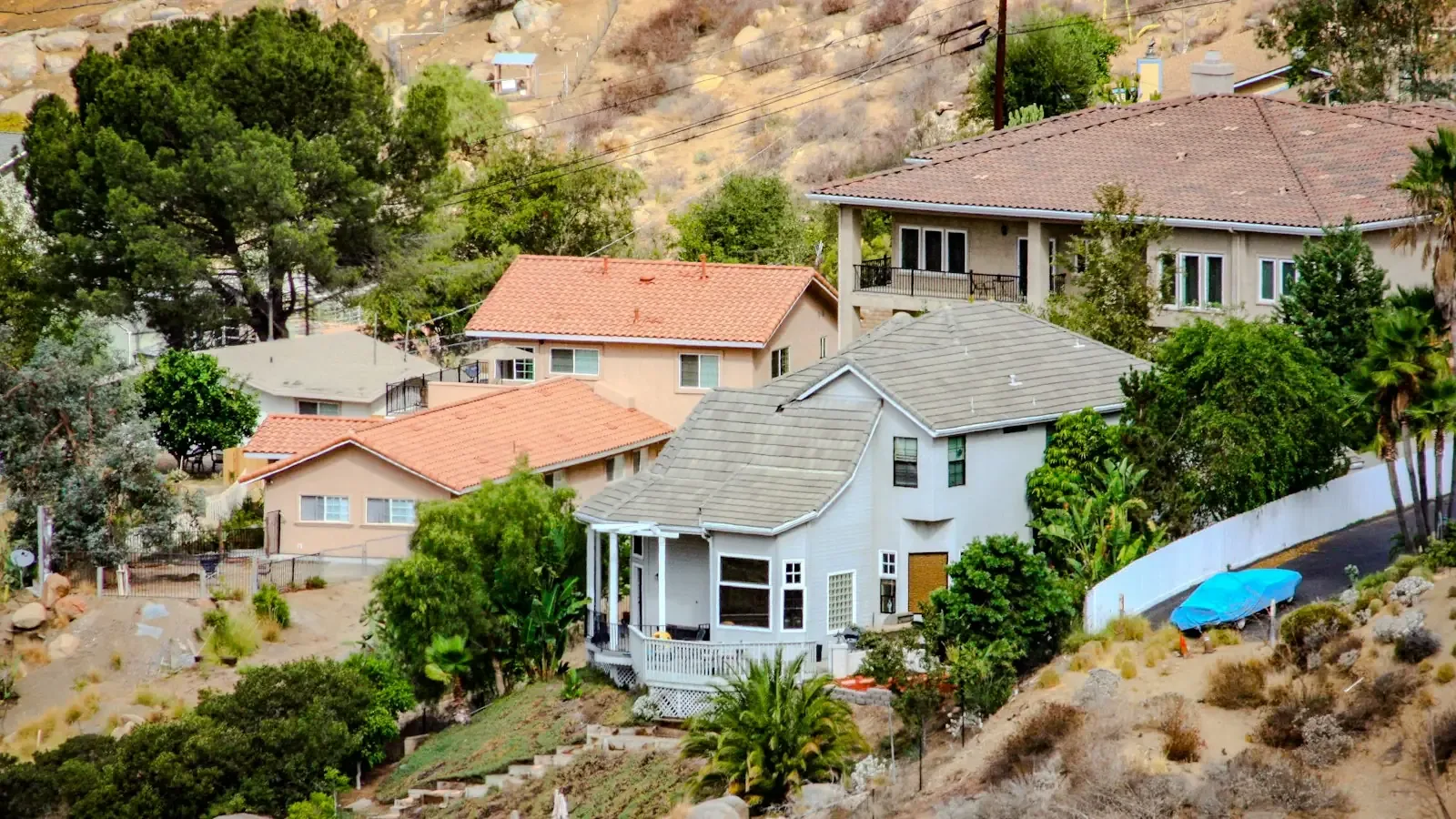 Hillside homes with tile roofs stepped up a dry slope above a Diamond Bar street